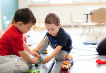Two young boys play with toy cars at a YMCA Child Care centre.