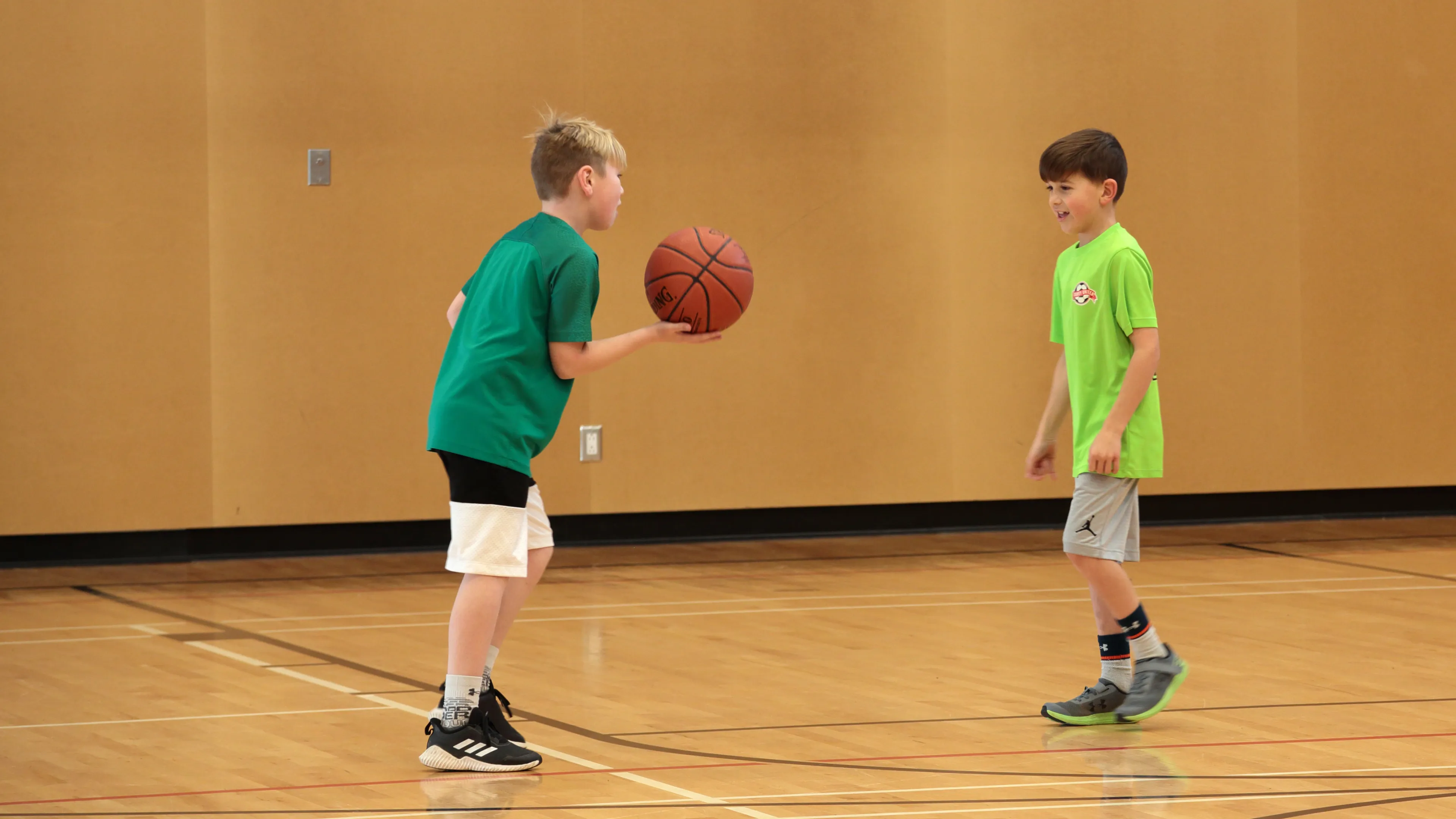 Two boys playing basketball in a gym