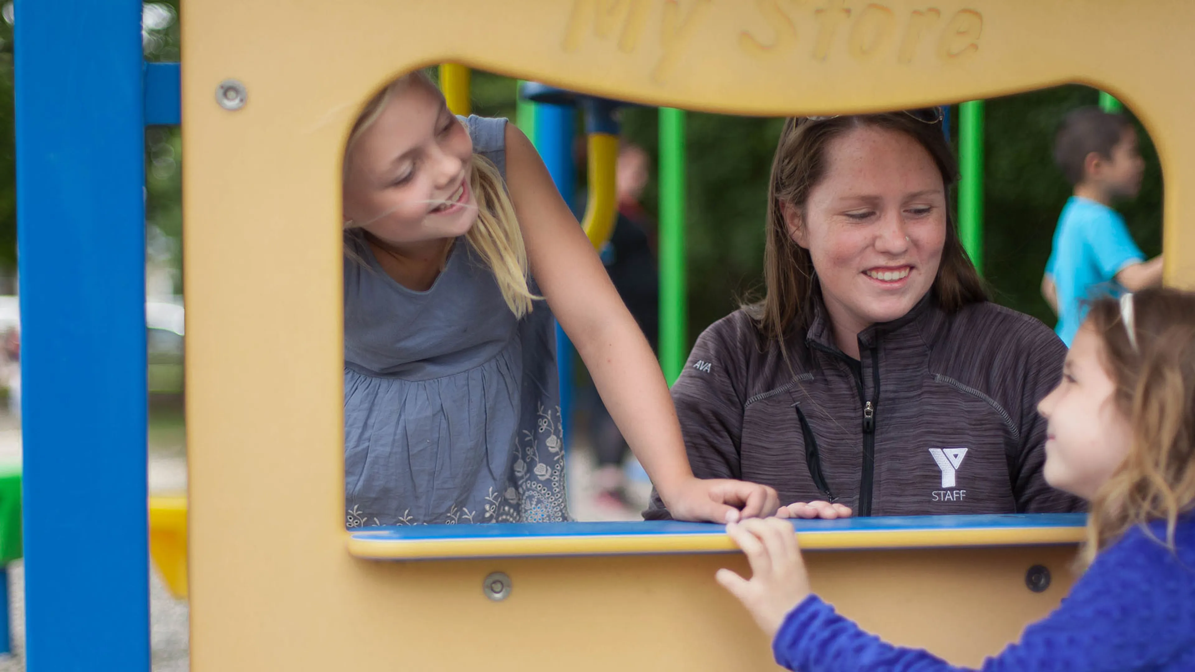 School Age Kids playing outside and interacting with a YMCA Staff member.