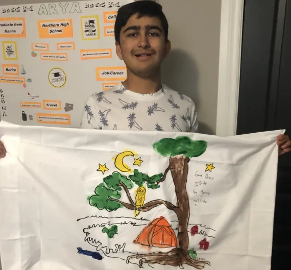 Camper Arya proudly shows artwork made with YMCA Autism Camp kits.