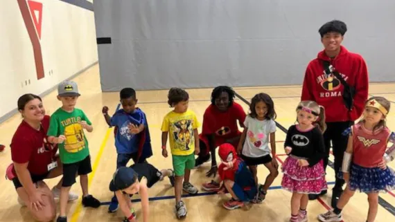 Two camp counsellors at Centre Branch YMCA pose with campers dressed as super heroes.