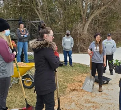 The staff at Indian Creek Child Care Centre prepare the outdoor gardens with shovels and a wheelbarrow.