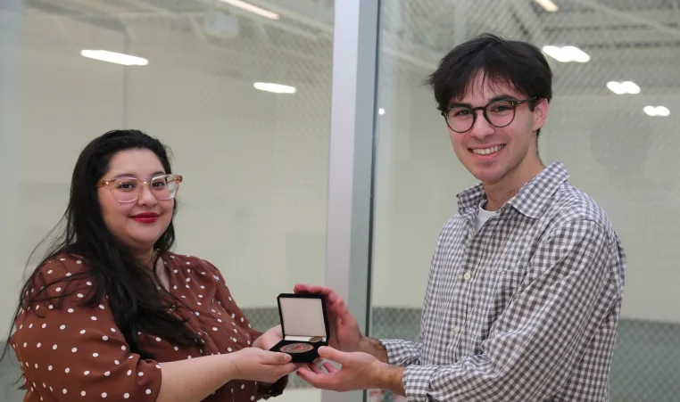 smiling woman with presenting a medal to a taller man 
