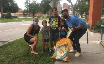 A family with three boys smile and pose with their Kids Club Kit.